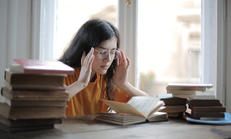 female-student-suffering-from-headache-in-library-3808057
